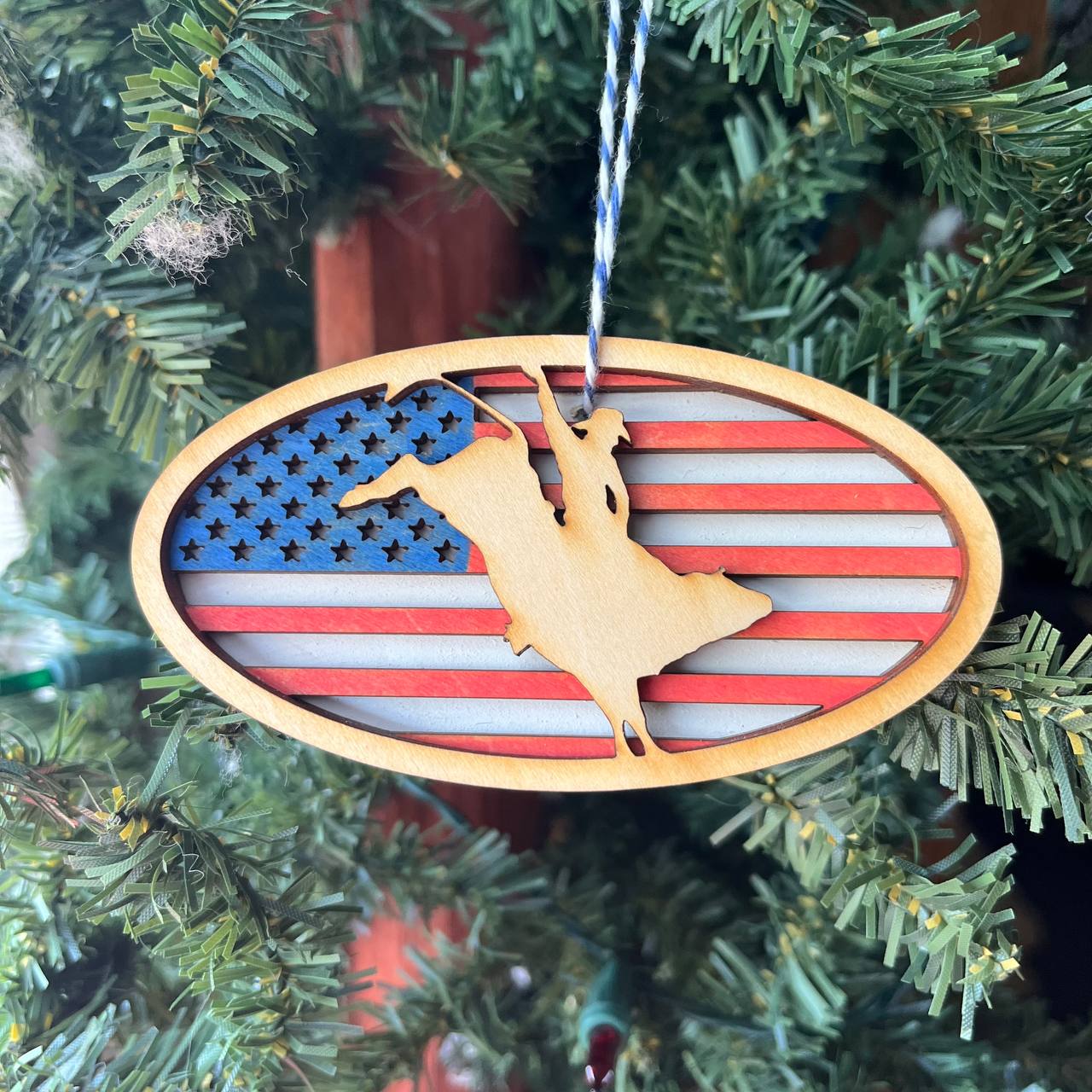 Patriotic Bull Rider Ornament – 4" Oval Wood Rodeo Christmas Ornament with American Flag Background for Cowboy & Western Decor