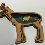 Wooden antelope shaped ornament with a landscape inset on a white background