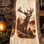 A rustic live-edge wooden sign featuring a detailed laser-burned or engraved stag in a mountain forest scene. The sign is displayed on a wooden surface next to a lit lantern and pinecones, with a wood-paneled background and the text 'NATURE INSPIRES HOME' in the upper left.