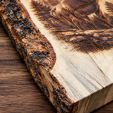Close-up of a rustic live-edge wooden board with bark on one side, featuring a detailed brown burned or engraved animal and forest design on the top surface, placed on a wood tabletop.