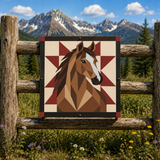A square decorative wall sign featuring a geometric brown horse head design on a cream and burgundy starburst background, mounted on a rustic wooden fence with mountains and trees behind it.