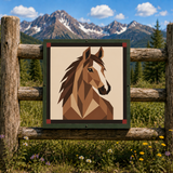 A framed square art print featuring a geometric brown horse head illustration, displayed on a rustic wooden fence with a mountain and forest landscape in the background.
