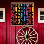 Feather Barn Quilt Pattern displayed on a rustic red barn with a vintage wagon wheel, showing the finished painted barn quilt outdoors.