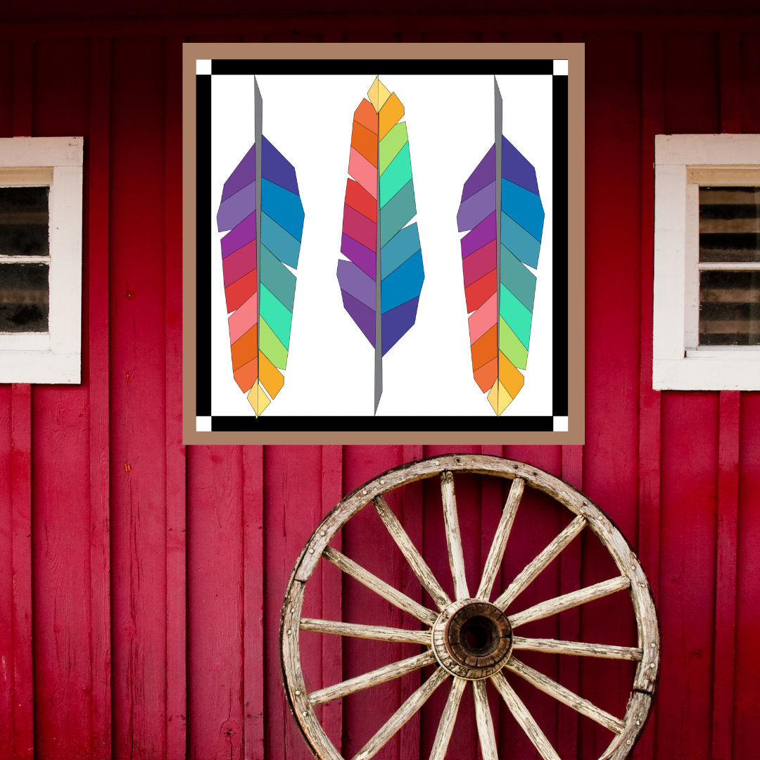 Feathers Barn Quilt Pattern displayed on a red barn with rustic wagon wheel, showing how the finished painted barn quilt looks outdoors.