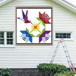 Hummingbird Barn Quilt Pattern displayed on the exterior of a farmhouse, illustrating how the finished painted quilt block looks on a home.