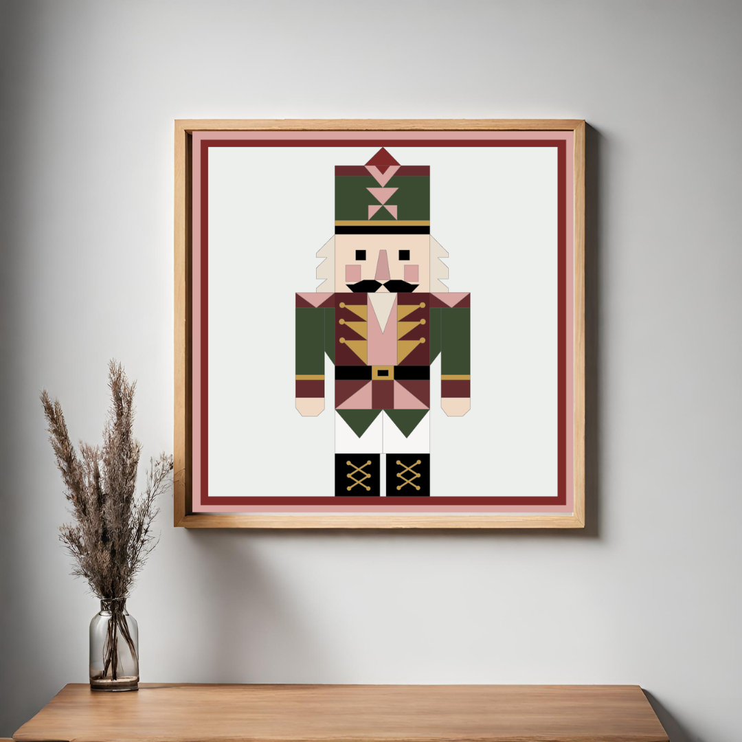 Framed wall art featuring a stylized nutcracker figure in geometric block colors, hung on a light gray wall above a wooden table with a small vase of dried grass.