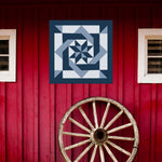 Pinwheel Knot  Barn Quilt Pattern displayed on a rustic red barn with a vintage wagon wheel, showing the finished painted barn quilt outdoors.