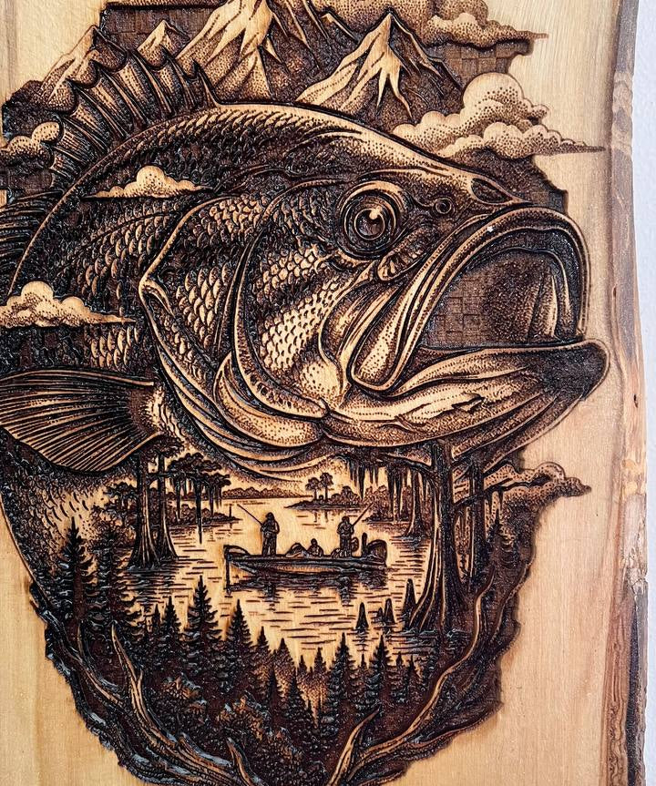 Wooden plaque with a detailed engraving of a fish, trees, and mountains.
