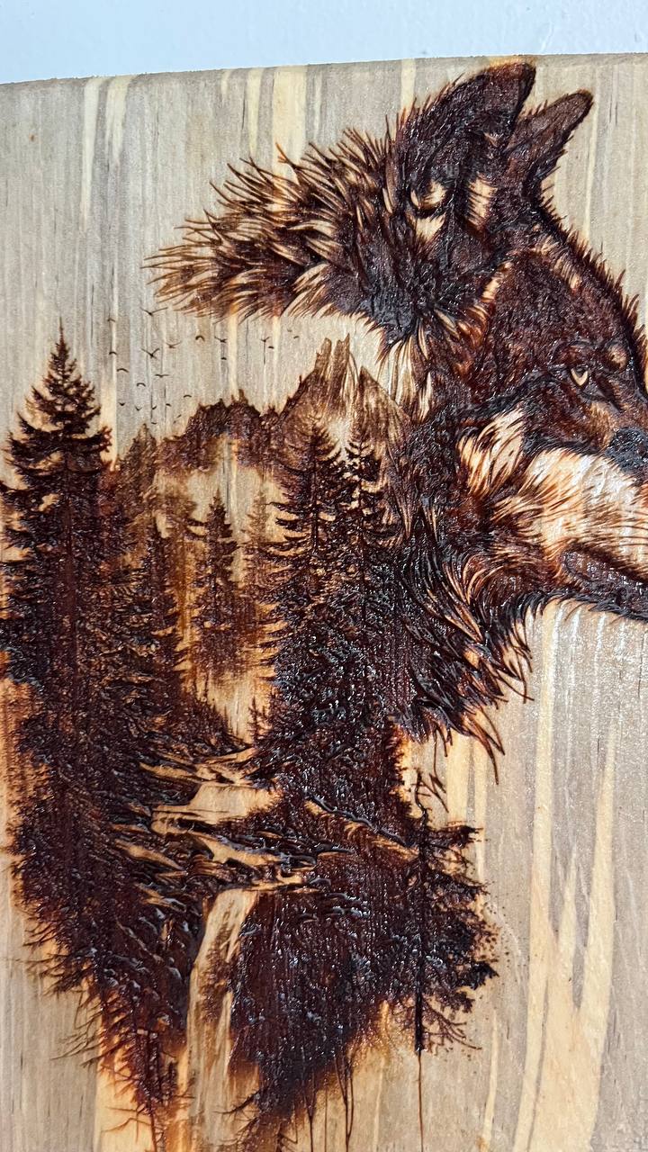 Wooden carving of two wolves with a forest background