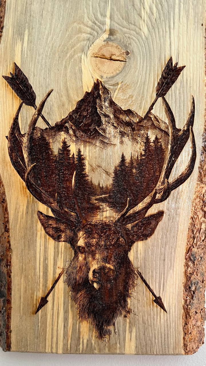 Wooden plaque with a deer head and antlers design, featuring a mountain and trees in the background.