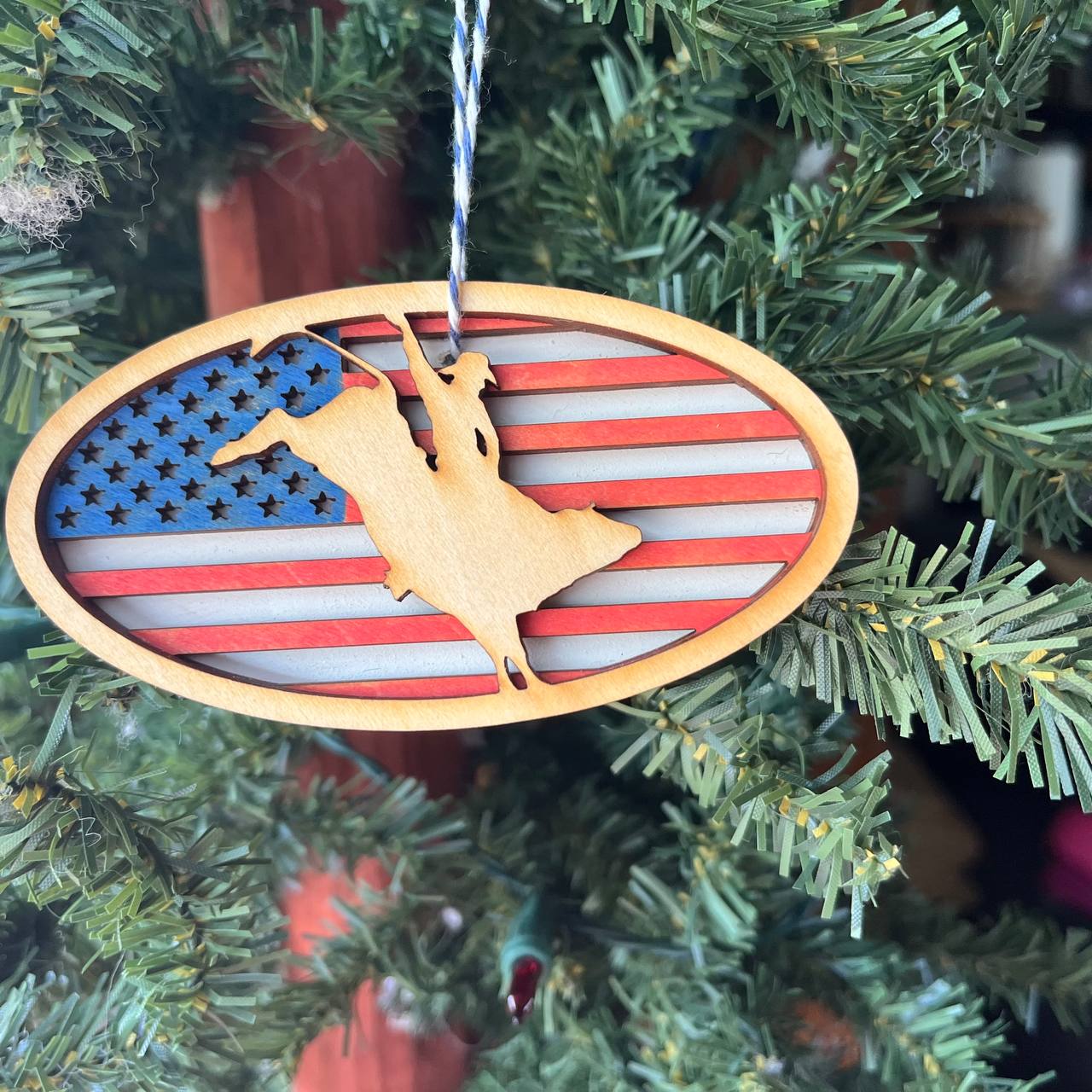 Patriotic Bull Rider Ornament – 4" Oval Wood Rodeo Christmas Ornament with American Flag Background for Cowboy & Western Decor