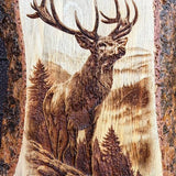 A live-edge wood plaque featuring a detailed laser-burned or engraved stag in a forest landscape, displayed on a stand.