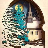 Handmade wooden Christmas book nook featuring a layered winter church, snow-covered evergreen trees and moonlit landscape for rustic Christmas bookshelf decor.